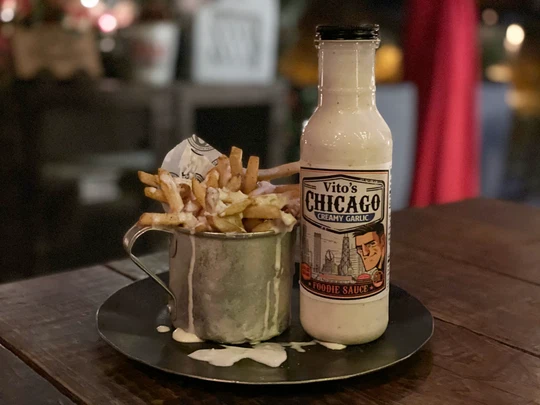 Bottle of Vito's Chicago Creamy Garlic Foodie Sauce beside garlic-sauced fries