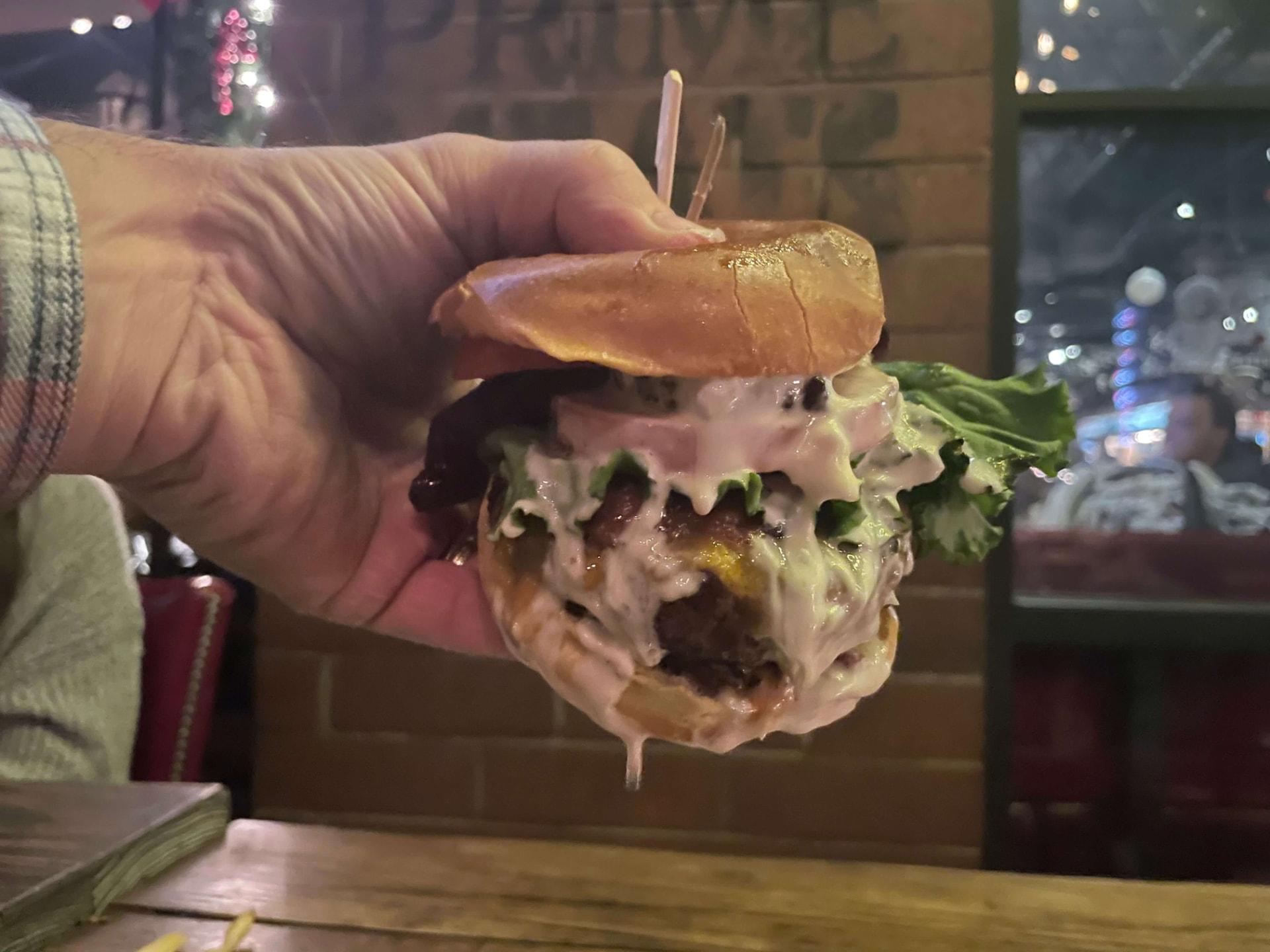 Hand holding a burger overflowing with Creamy Garlic Foodie Sauce